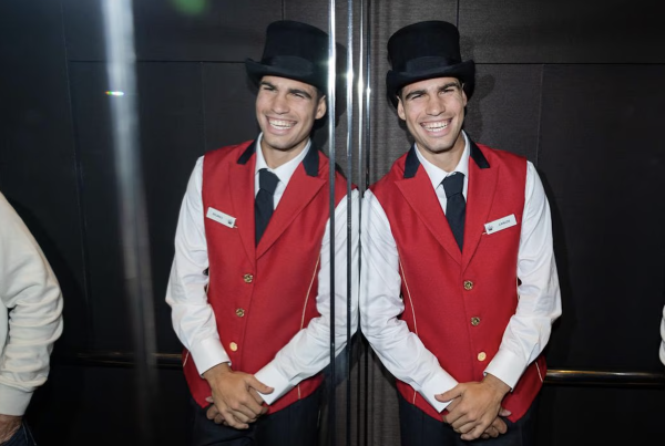 Carlos Alcaraz poses in a Crown Hotels elevator, dressed in a doorman outfit.